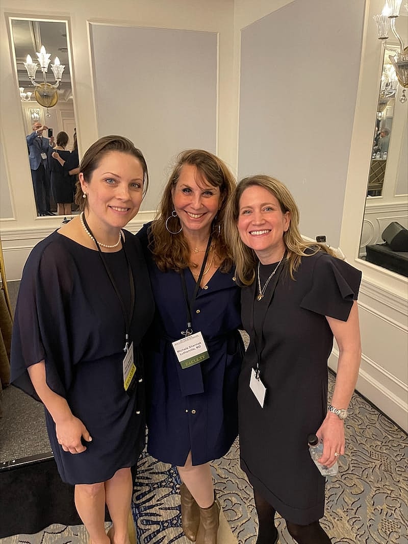 Three women smiling at an event.