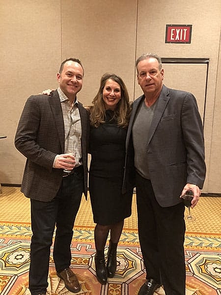 Three people posing together at an event.