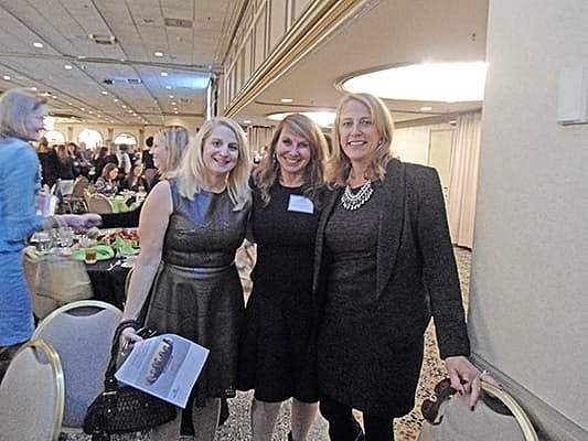 Three women posing at an event.