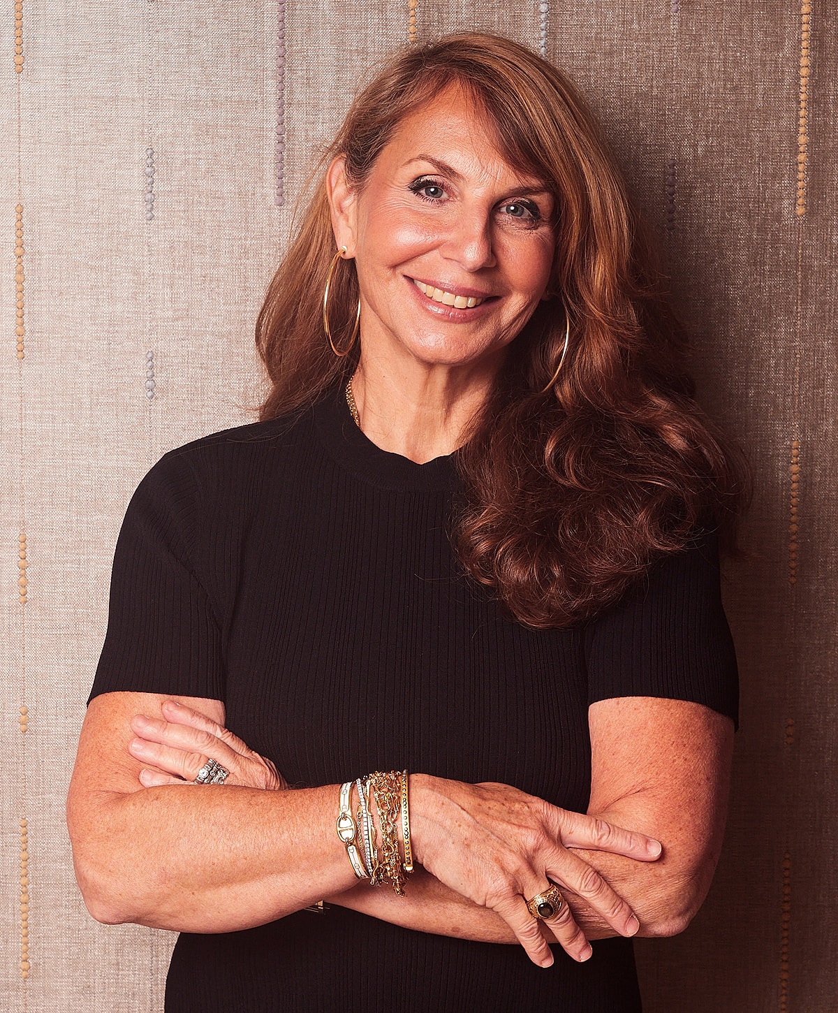 Smiling woman with long hair and bracelets.