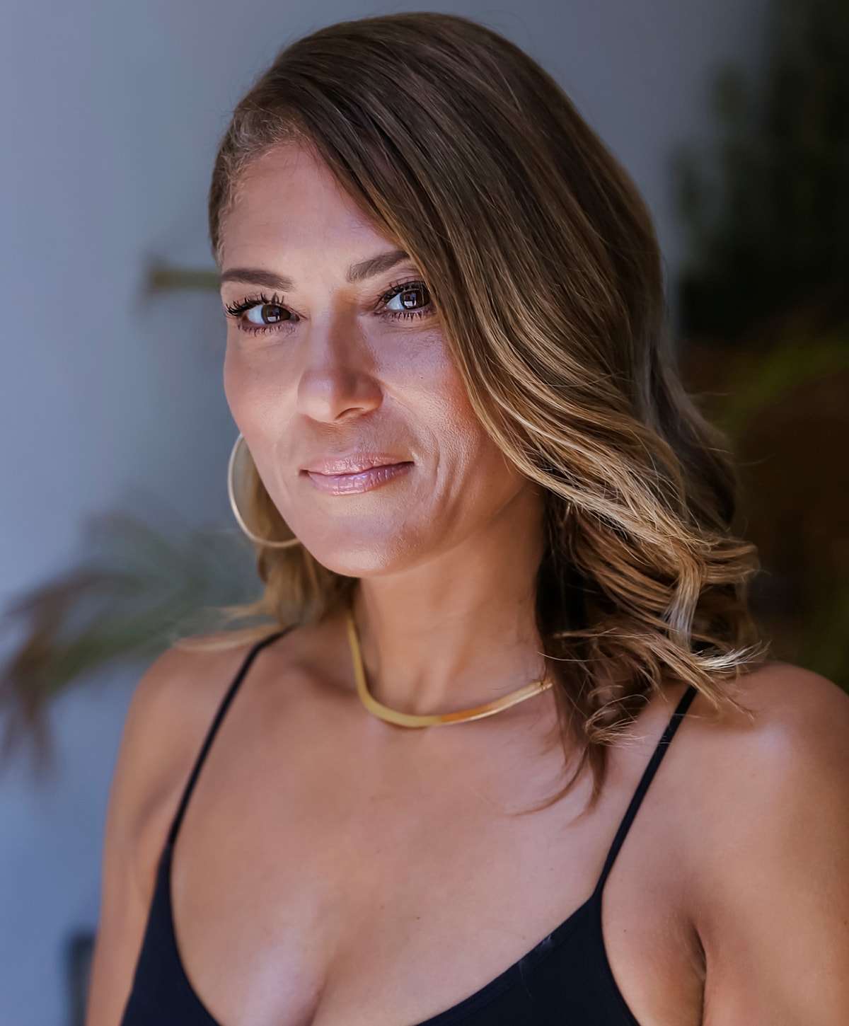 Woman with wavy hair and gold necklace.