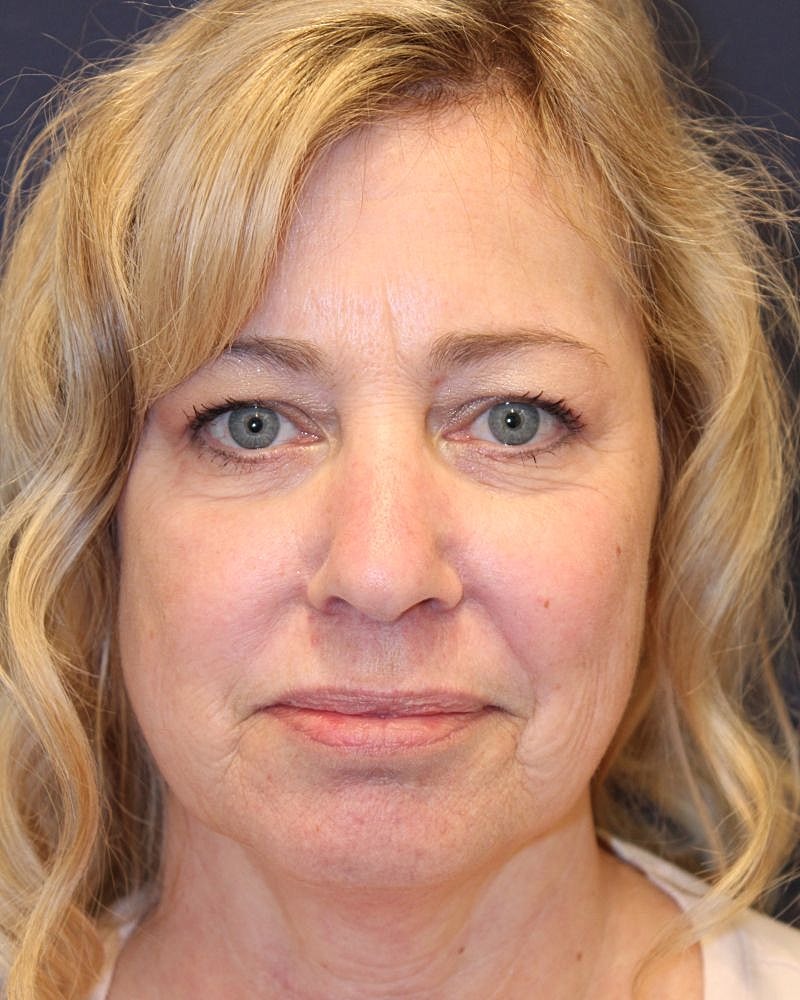 Smiling woman with wavy hair and blue eyes.