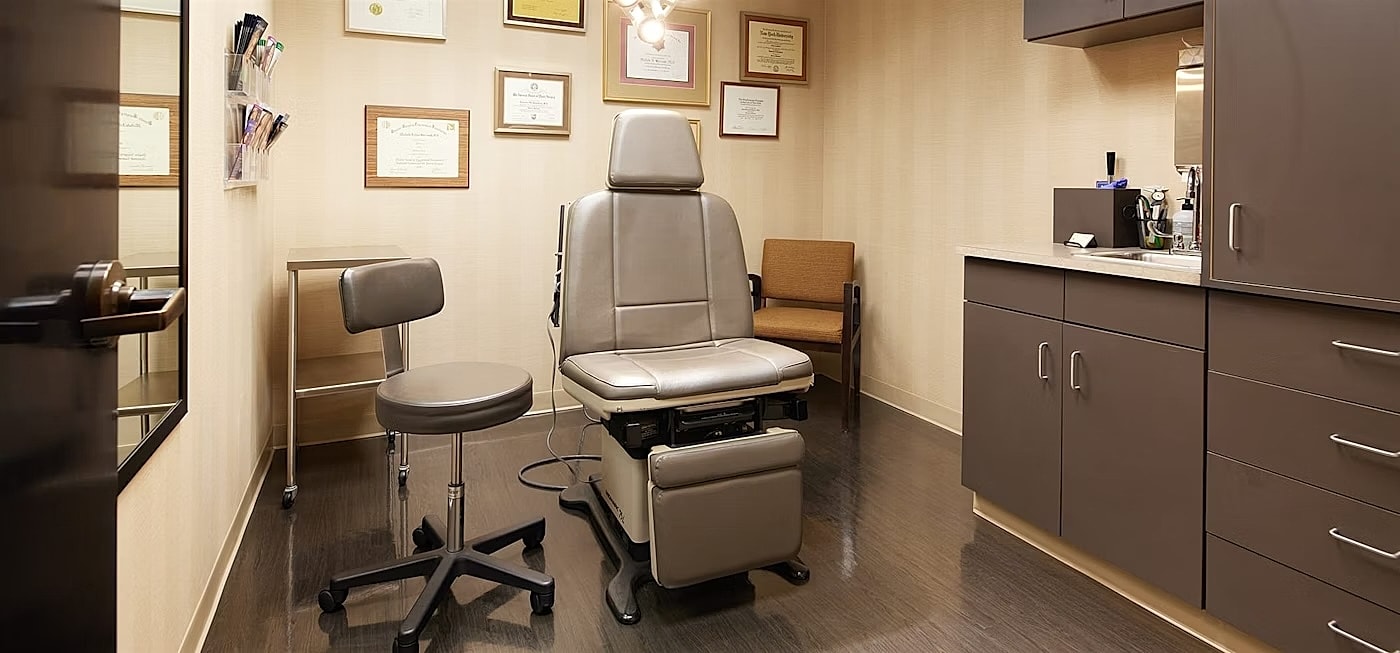 Medical examination room with chair and certificates.