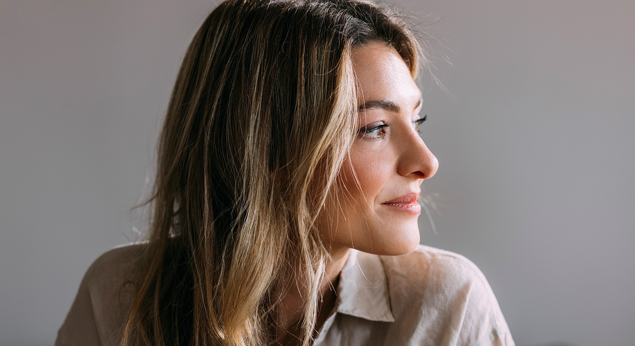 Woman smiling softly, profile, natural lighting.