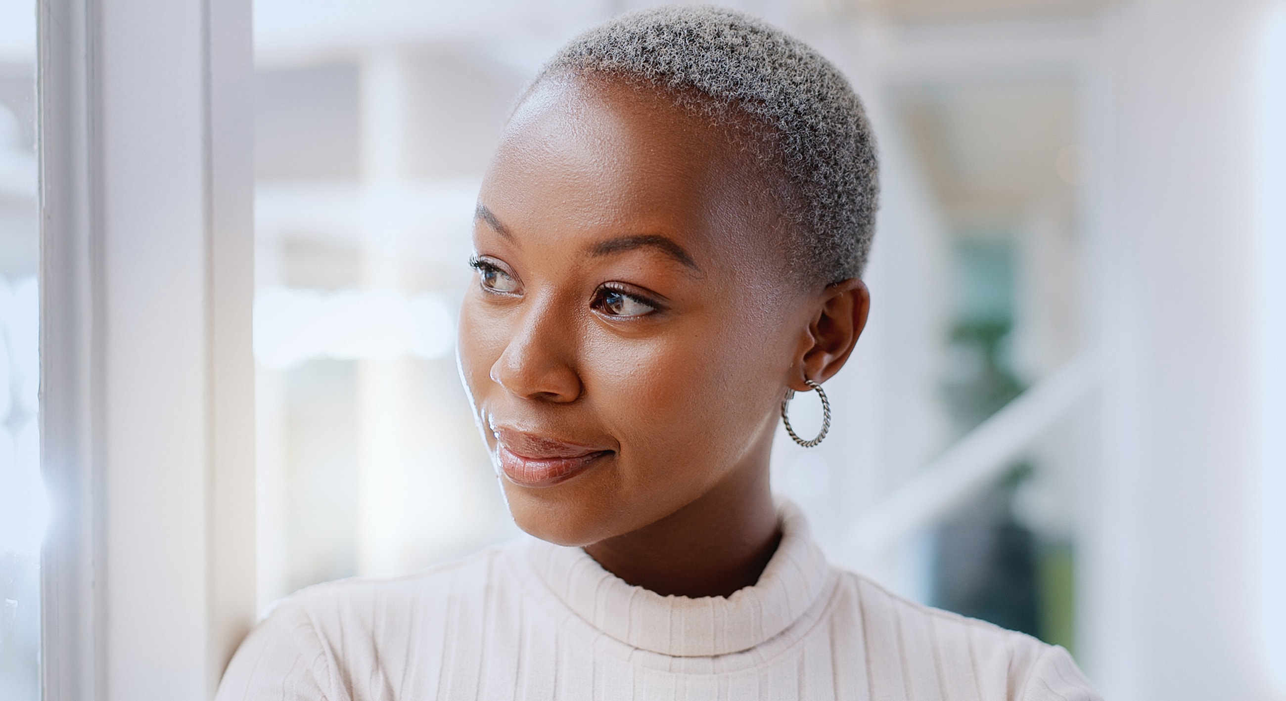 Woman with short hair looking thoughtfully indoors.